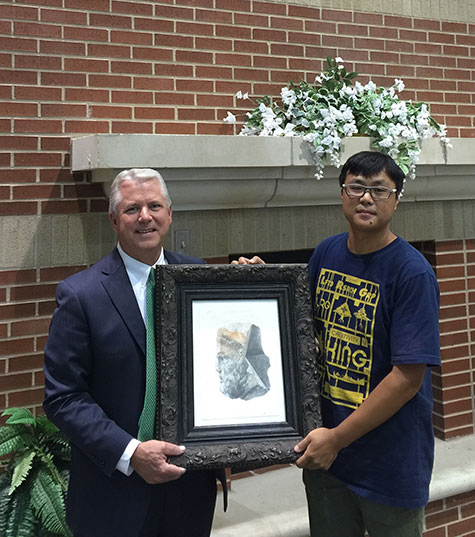 Junfeng Guo and President Turner holding original pencil and watercolor sketch by Guo